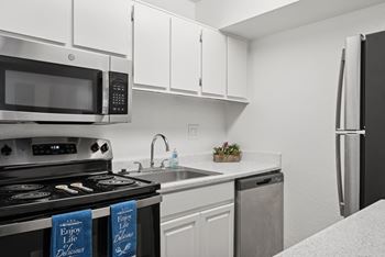 A kitchen with a stove, microwave, and refrigerator.